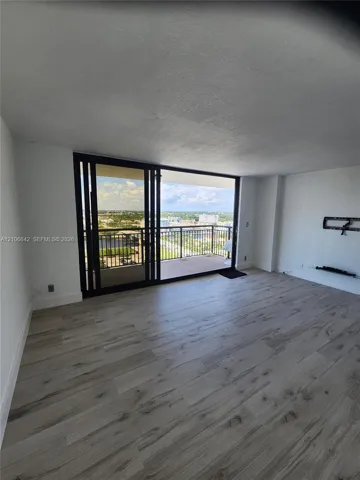Living area featuring wood-finish flooring, floor-to-ceiling sliding glass doors, and a private balcony with metal railings
