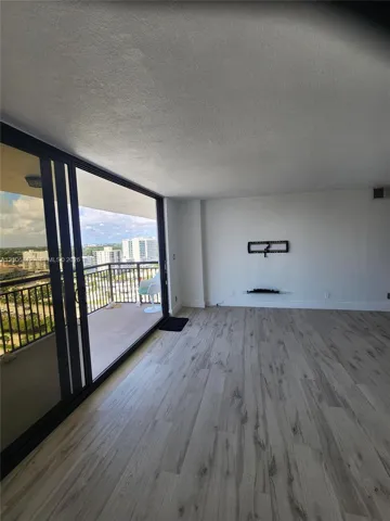 Floor-to-ceiling sliding glass doors, private balcony with metal railing, and wood-finish flooring