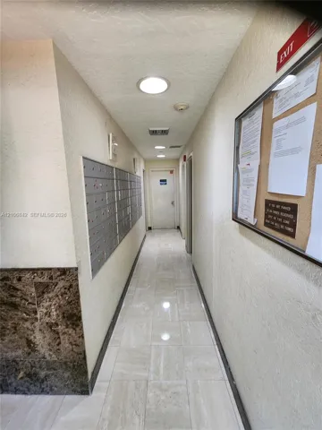Interior corridor featuring stone-finish floor tiling, wall-mounted mail lockers, recessed lighting, and decorative stone-textured wall accents