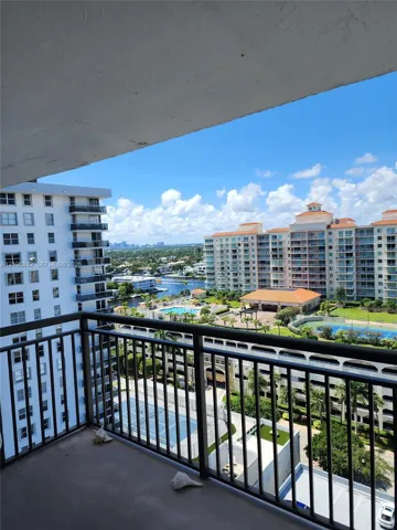 Private balcony with metal railing, overlooking urban buildings, a swimming pool, and a tennis court