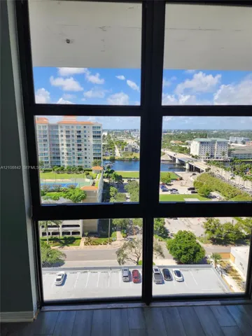 Floor-to-ceiling windows featuring black framing, showcasing expansive exterior sights including a waterfront, multi-story urban buildings, and surrounding landscaping