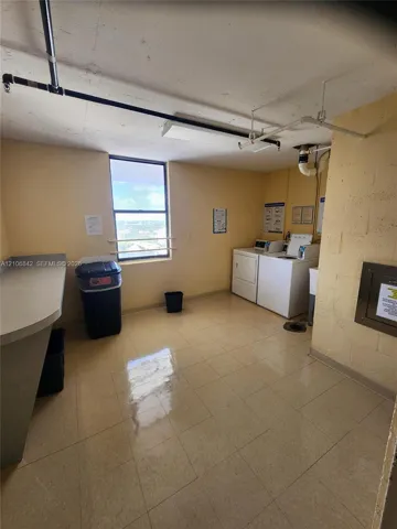 Laundry room featuring tile flooring, a dedicated workstation with a solid-surface countertop, and a window with exterior exposure