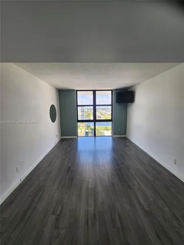 Living area featuring wood-finish flooring, floor-to-ceiling windows, and painted accent walls