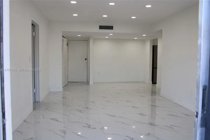 Interior space featuring high-gloss, large-format veined tile flooring, crisp white walls, and recessed ceiling lighting