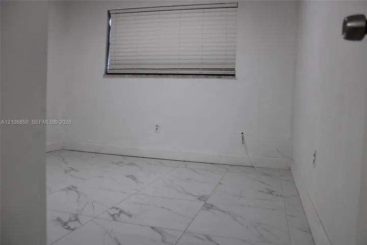 Interior space featuring white stone-finish tile flooring and an integrated horizontal window blind