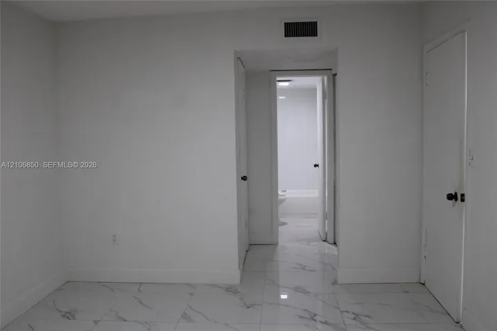 Polished large-format tile flooring with marble-finish detailing, solid-core interior doors, and neutral wall finishes