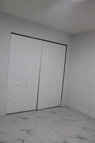 Large-format stone-patterned tile flooring and dual-panel white closet doors