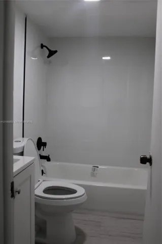 Full bathroom featuring a tub-shower combination with matte black fixtures, white surround, and a vanity cabinet