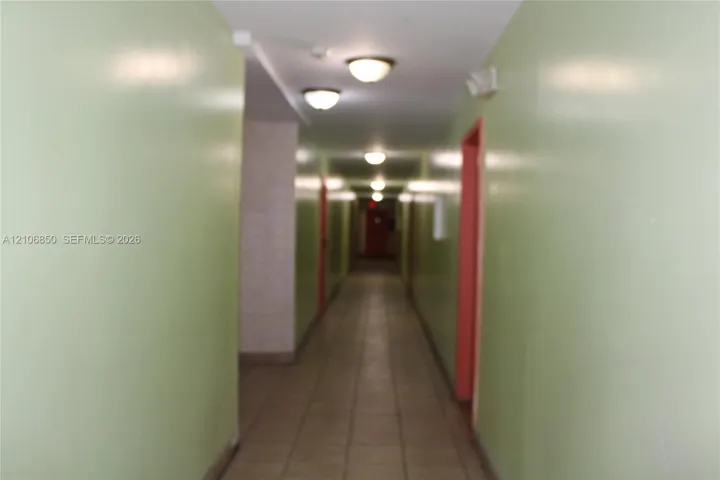 Interior corridor featuring tiled flooring, painted walls, and ceiling-mounted dome light fixtures