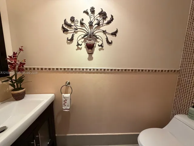 Wall-mounted vanity featuring a white basin, two-toned wall paint, decorative tile border inlay, and small-format mosaic wall tile