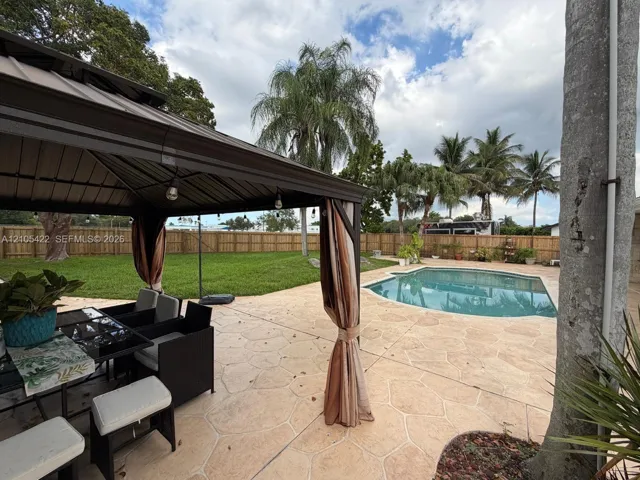 Backyard featuring a metal-frame gazebo, stamped concrete patio, inground swimming pool, and privacy wood fencing