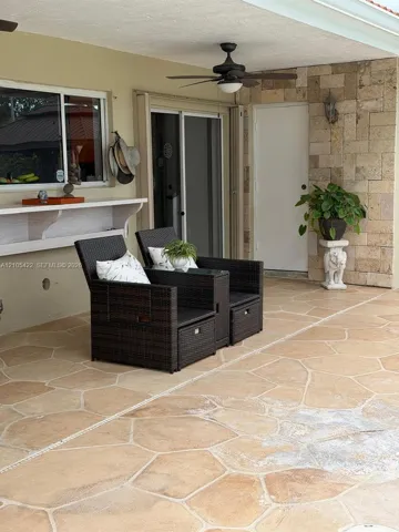 Covered patio featuring flagstone flooring, a natural stone veneer accent wall, built-in shelving, and a ceiling-mounted fan