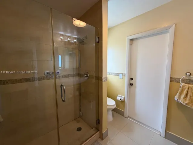 Walk-in shower with a glass enclosure, tile surround, decorative mosaic tile inlay, and integrated plumbing fixtures, featuring large-format tile flooring