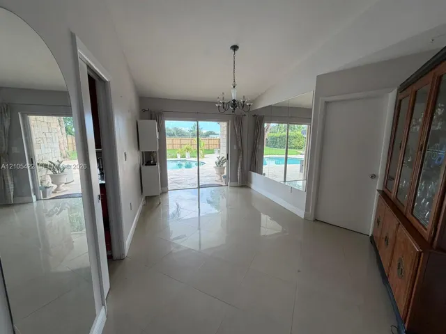 Large-format tile flooring, oversized wall-mounted mirrors, and sliding glass doors with direct exterior access to a paved pool area
