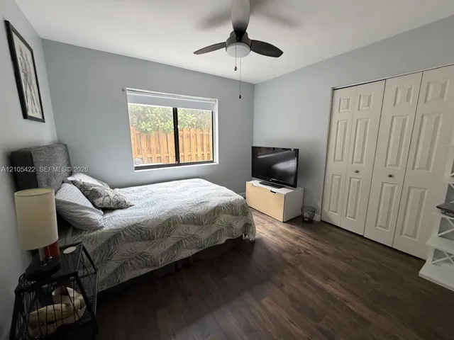 Room featuring wood-finish flooring, dual-panel closet doors, and a ceiling fan with integrated lighting