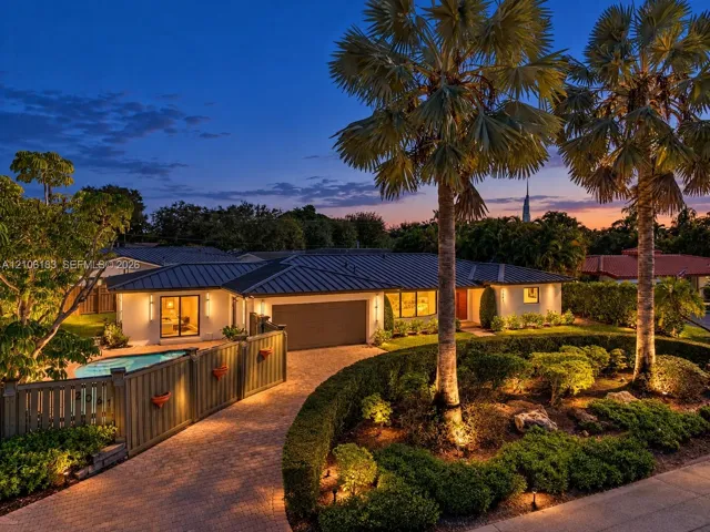 Single-story residence featuring a metal roof, paver driveway, attached garage, private swimming pool, and professional landscaping