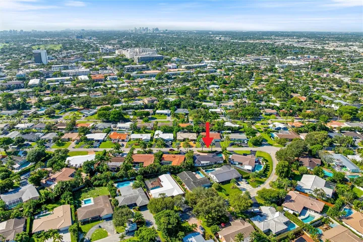 Aerial perspective of a residential property featuring a low-pitch roof, a multi-car driveway, and mature landscaping