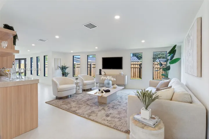 Open-concept interior featuring light-toned tile flooring, recessed ceiling lighting, vertical windows, and a built-in cabinetry unit