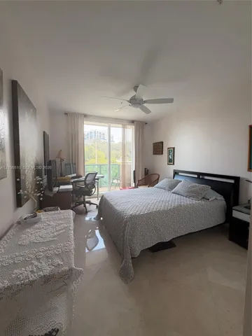 Room featuring light-toned tile flooring, ceiling fan with integrated lighting, and glass sliding doors providing exterior balcony access