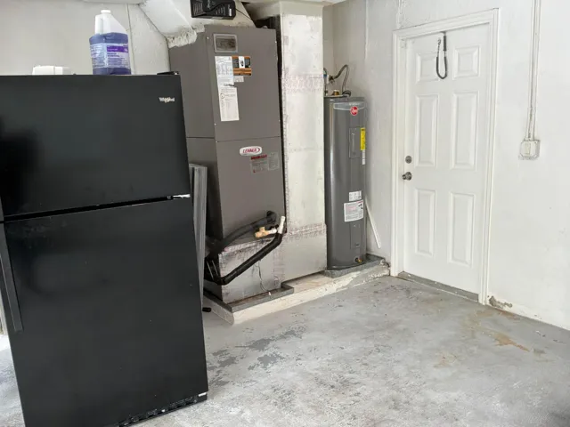 Utility area featuring a vertical furnace, water heater, and a multi-panel exterior access door