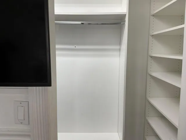 Custom built-in closet system featuring white shelving, integrated hanging rod, and adjustable-height storage compartments