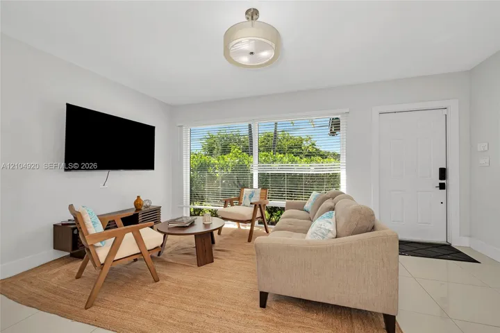 Large format tile flooring, expansive multi-pane window, drum-style ceiling fixture, and a solid six-panel exterior entry door