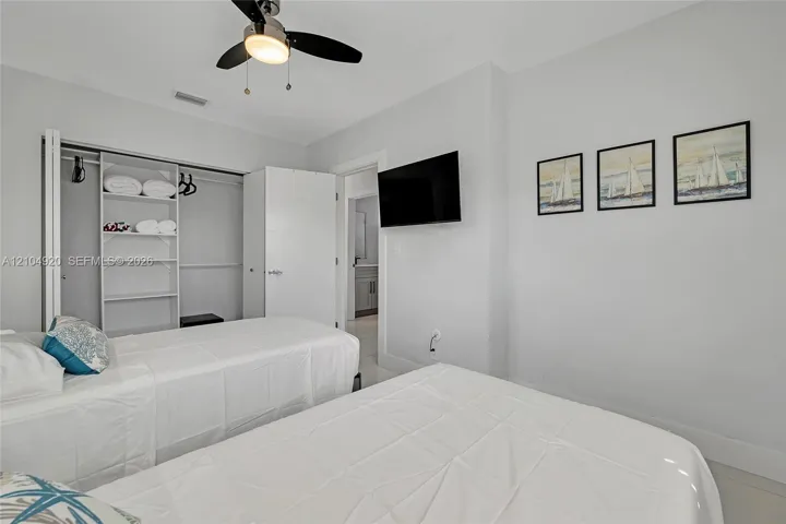 Bedroom featuring high ceilings, a ceiling fan with integrated lighting, and a reach-in closet with built-in shelving