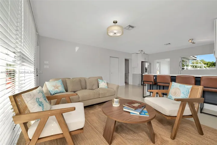 Open-concept living space featuring high-gloss tile flooring, neutral wall tones, recessed lighting, and a breakfast bar with built-in cabinetry