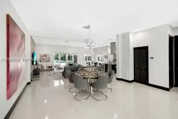 Open-concept interior featuring large-format tile flooring, a stone-accent wall, recessed lighting, and a crystal chandelier