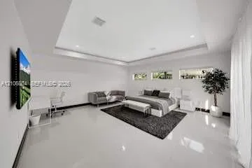 Spacious room featuring a deep tray ceiling, high-gloss tile flooring, and three horizontal clerestory windows