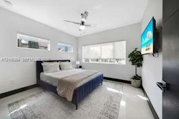Neutral-toned room featuring high-gloss flooring, recessed lighting, a modern ceiling fan, and large windows providing natural light