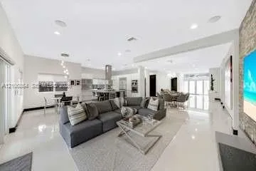 Open-concept interior featuring large-format tile flooring, recessed lighting, a stone-accent wall, and a kitchen island with built-in cabinetry