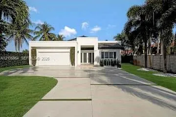 Modern single-story exterior featuring a white stucco facade, multi-car garage, concrete paver driveway with integrated landscaping strips, and manicured perimeter lawn
