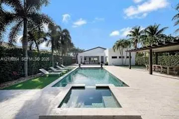 In-ground swimming pool with an attached spa, expansive stone paver pool deck, and timber-framed pergola