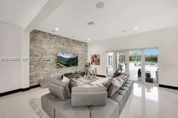 Living area featuring stacked stone accent wall, large-format tile flooring, recessed lighting, and multi-panel sliding glass doors