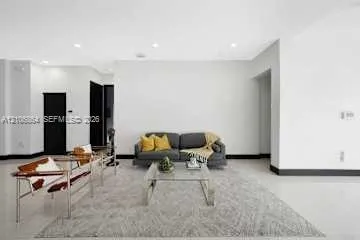 Open-concept living space featuring high ceilings with recessed lighting, crisp white wall finishes, polished hard-surface flooring, and high-contrast dark door frames