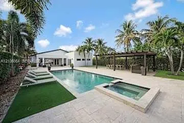 Outdoor living space featuring an in-ground swimming pool, raised spa, stone-finish patio, and a covered pergola