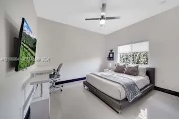 Neutral-toned interior featuring gloss-finish flooring, a multi-blade ceiling fan with integrated light, and a window with roller shade