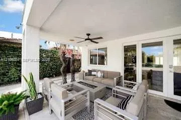 Covered patio featuring a recessed ceiling, mounted ceiling fan, stone-style flooring, and glass-paneled entry doors