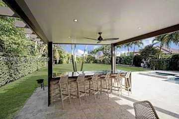 Covered patio featuring a built-in outdoor bar with stone veneer, recessed ceiling lighting, a ceiling fan, and stone-tile flooring