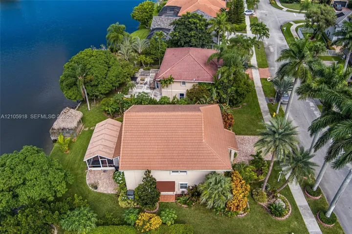 Waterfront property featuring a tile roof, a screened-in patio, paver hardscaping, and mature landscaping
