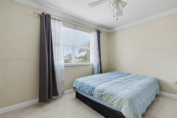 Neutral wall finishes, crown molding, and a ceiling-mounted light fixture with fan