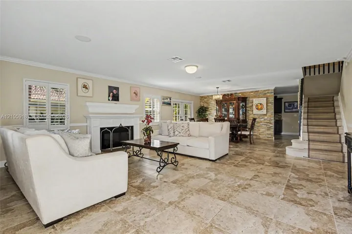 Living area featuring tile flooring, a fireplace with a white mantel, stone-accented wall, and a staircase with a runner