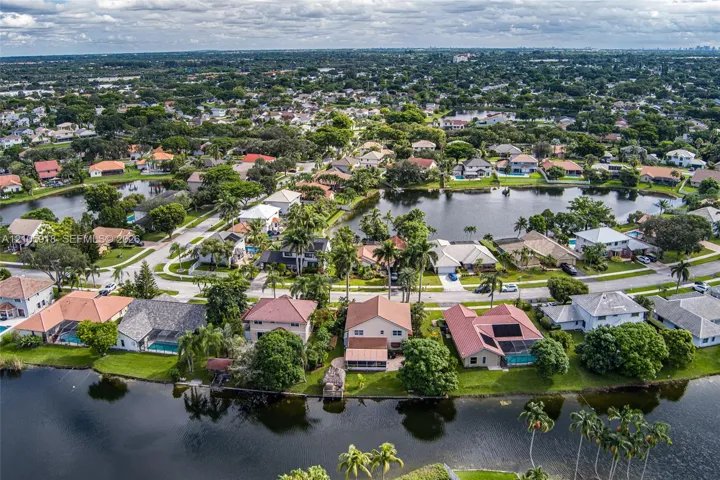 Aerial perspective featuring waterfront property positioning, multiple canal-front lots, mature tropical landscaping, and paved street infrastructure