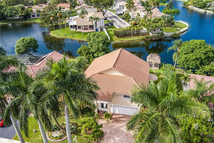 Waterfront property featuring a tile roof, paver driveway, and mature palm trees