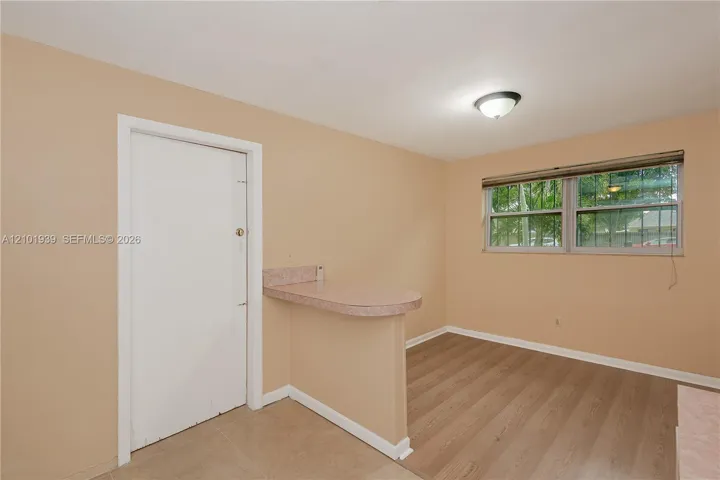 Wood-finish flooring, half-wall breakfast bar with a laminate countertop, and double-pane window featuring integrated security bars