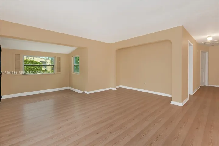 Interior space featuring wood-finish flooring, neutral wall paint, and an arched entryway