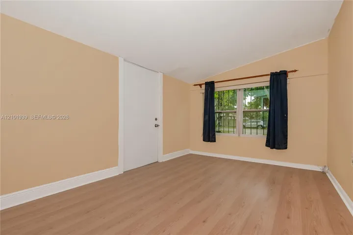 Interior space featuring vaulted ceilings, wood-finish flooring, and windows with integrated security bars