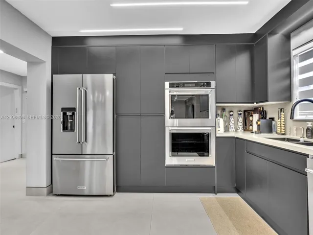 Sleek charcoal cabinetry, stainless steel double wall ovens, French door refrigerator, light-toned countertop, and integrated linear overhead​​‌​​​​‌​​‌‌​‌‌​​​‌‌​‌​‌​‌​​​‌​​ lighting
