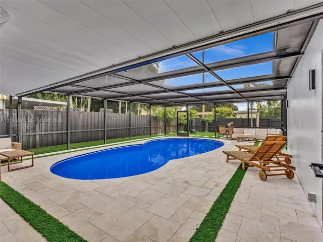 Screened-in patio featuring a swimming pool, stone-paver decking, integrated turf accents, and full-perimeter privacy fencing
